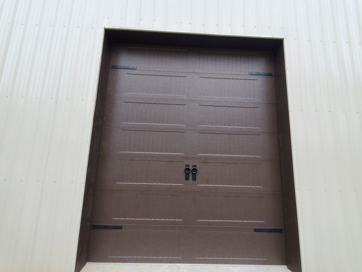 Brown industrial loading dock door set in a white corrugated wall.