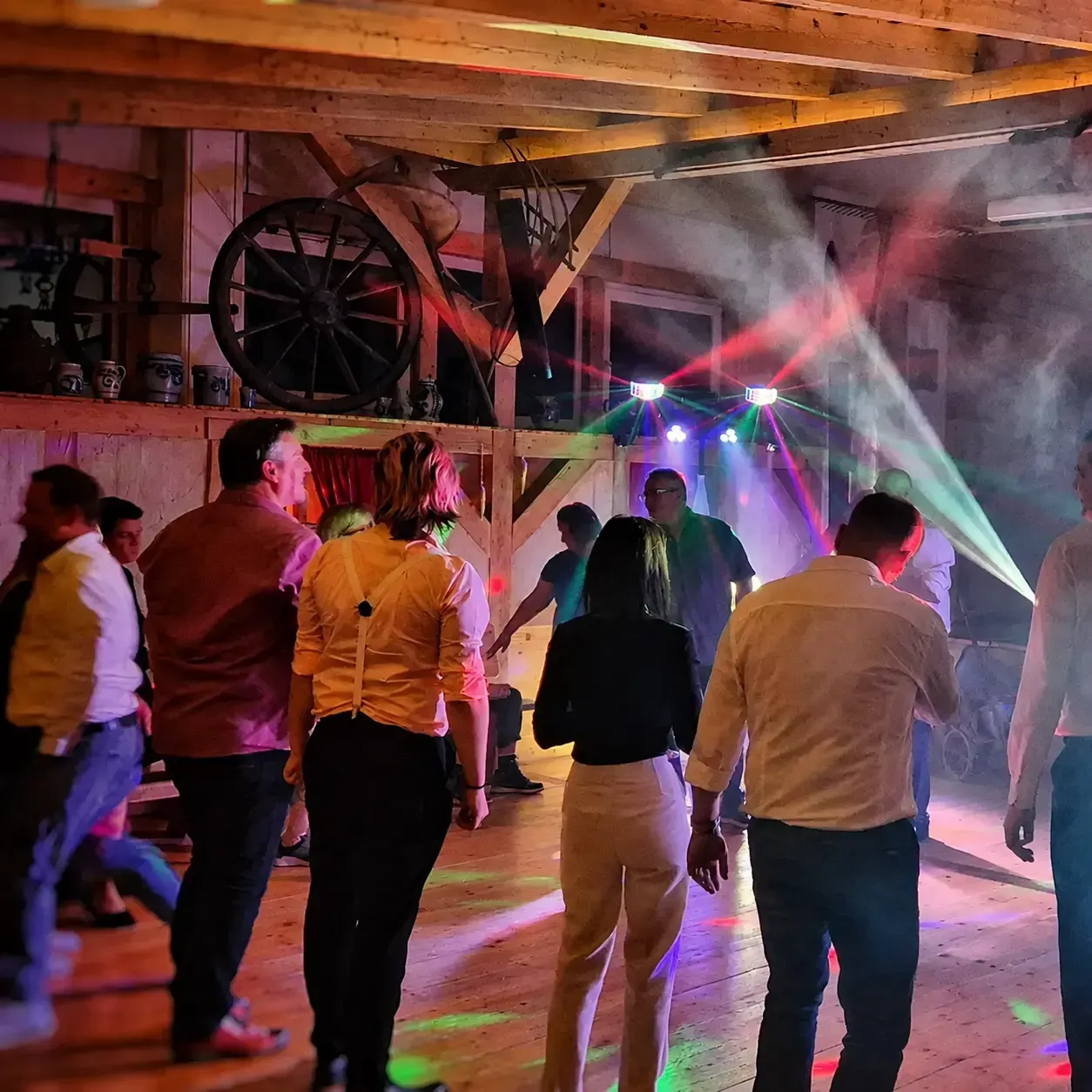 Feiernde Gäste in einer Holzlocation mit sichtbaren Lichtstrahlen
