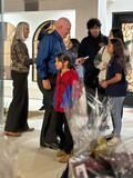 People chatting at an indoor event, with wrapped gift baskets in the foreground.