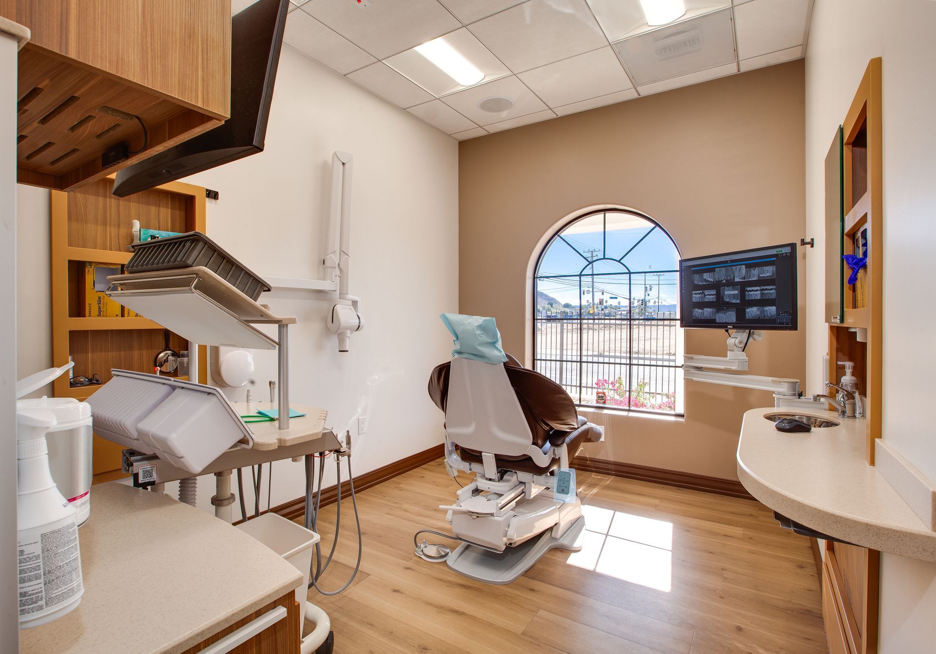 Modern dental exam room with chair, equipment, and window light