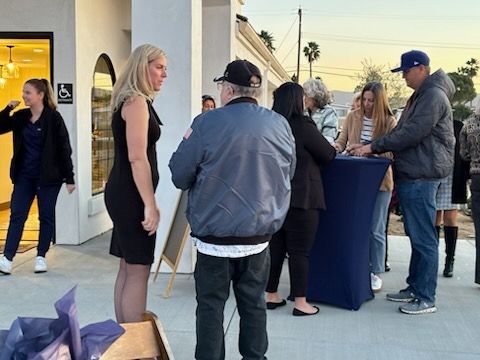 People mingling outdoors at a social event near a high table at sunset