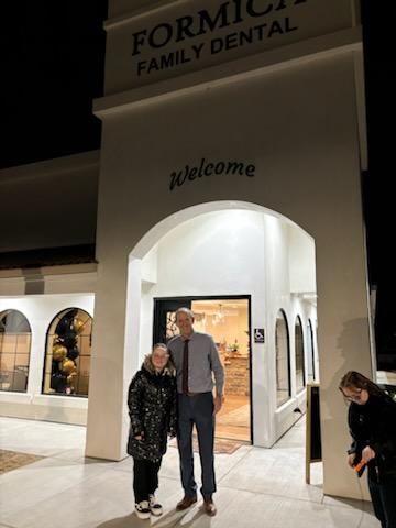 Two people standing outside a lit dental office entrance at night, with “Welcome” above the archway