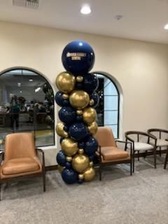 Blue and gold balloon column beside tan chairs in a lobby waiting area