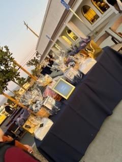 Outdoor buffet table with black cloth, platters, flowers, and framed signs at a patio event