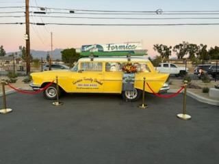 Yellow vintage car on display at dusk, roped off outside a Formica sign.