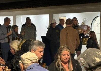 Crowded indoor gathering with people standing and sitting in a bright room