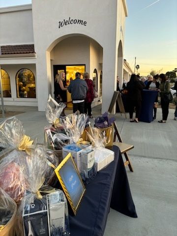 Outdoor welcome entrance with gift baskets and framed plaques on display near a group of people