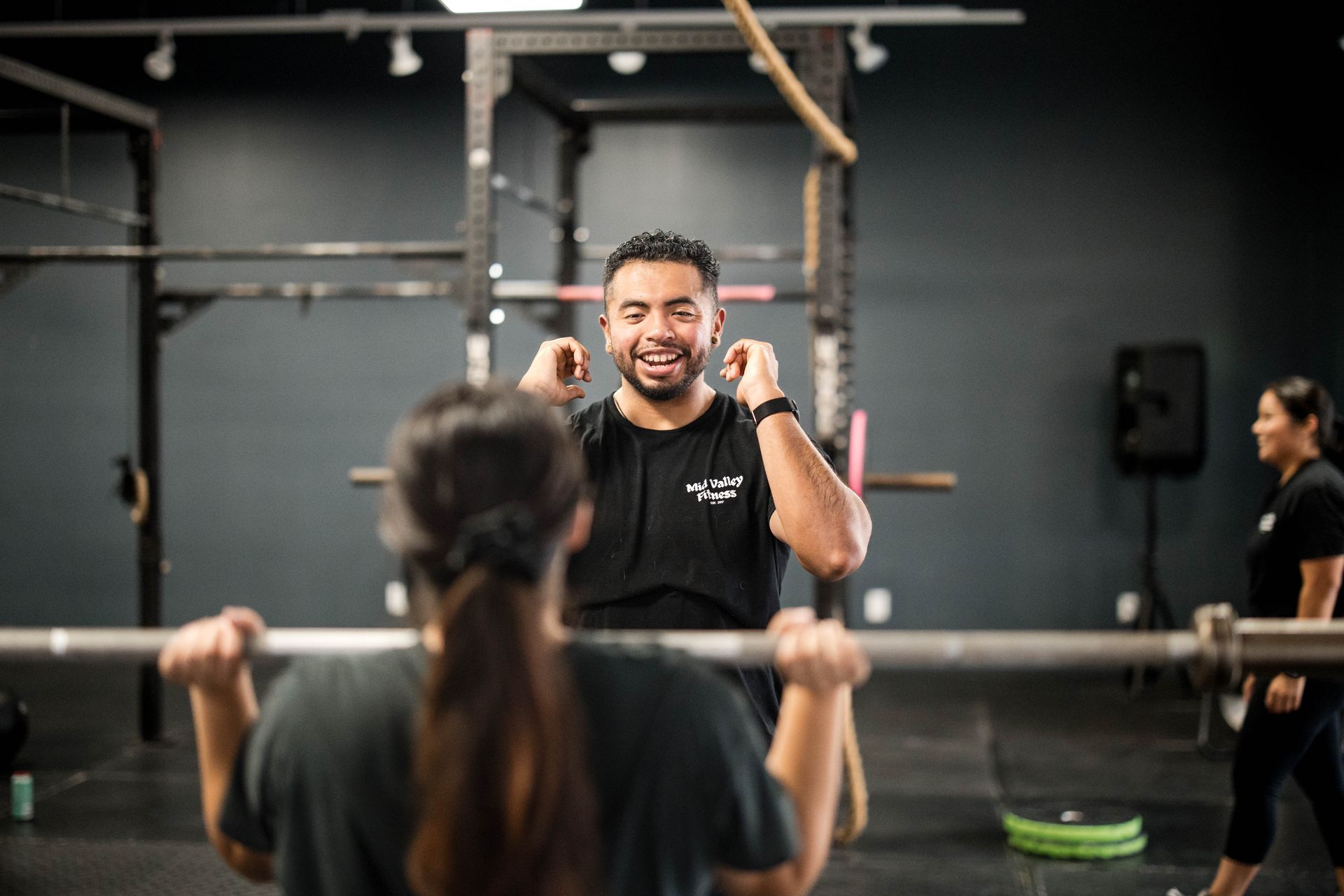 A man is doing dips with a trainer in a gym.