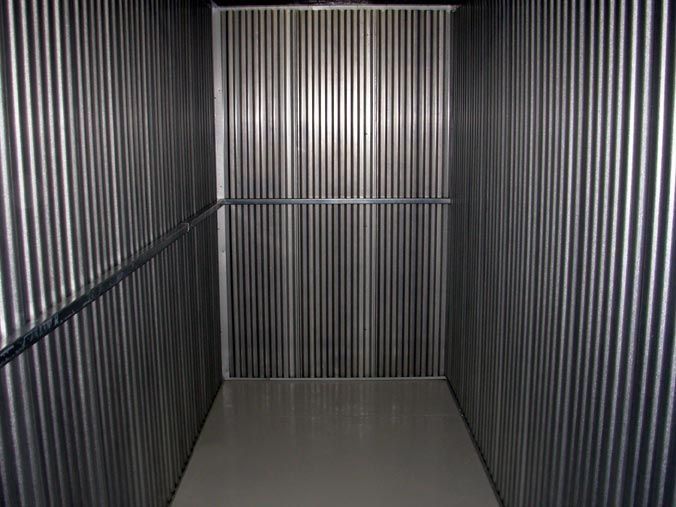 An empty elevator with a metal wall and a white floor.