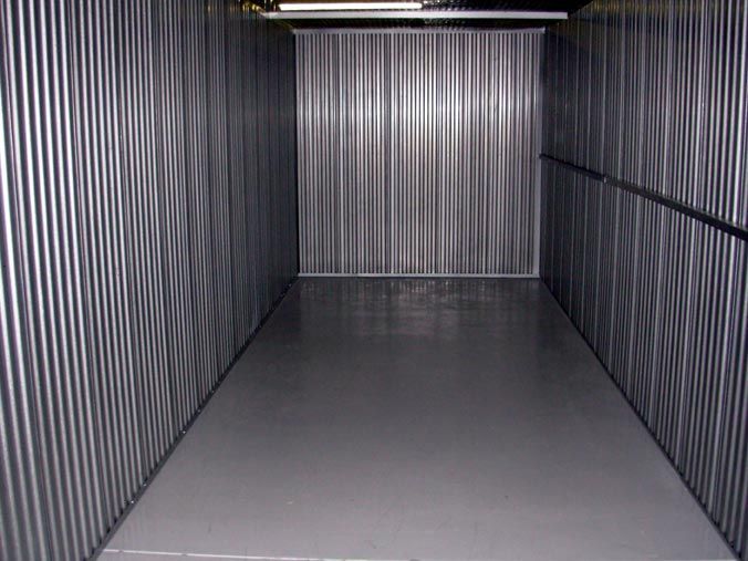 An empty room with a metal wall and a gray floor.