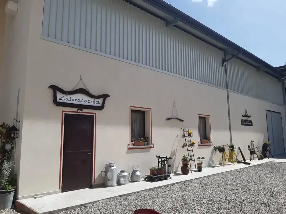 Un edificio beige con una porta scura, piccole finestre e elementi decorativi in metallo sulla parete esterna.