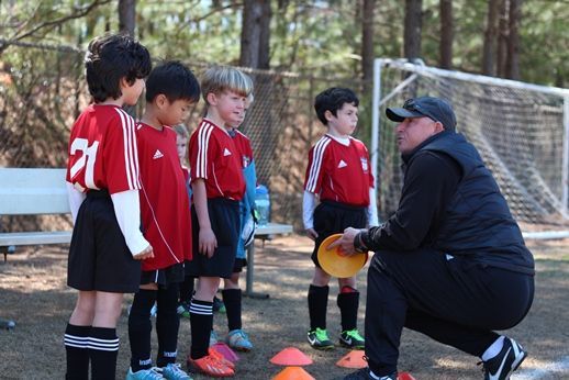 A youth team standing with their Ambush Junior Academy coach
