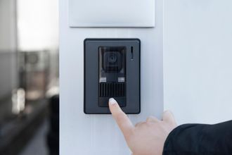 A person is pressing a button on a wall with their finger.