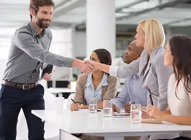 Business team in a meeting room, shaking hands across a conference table