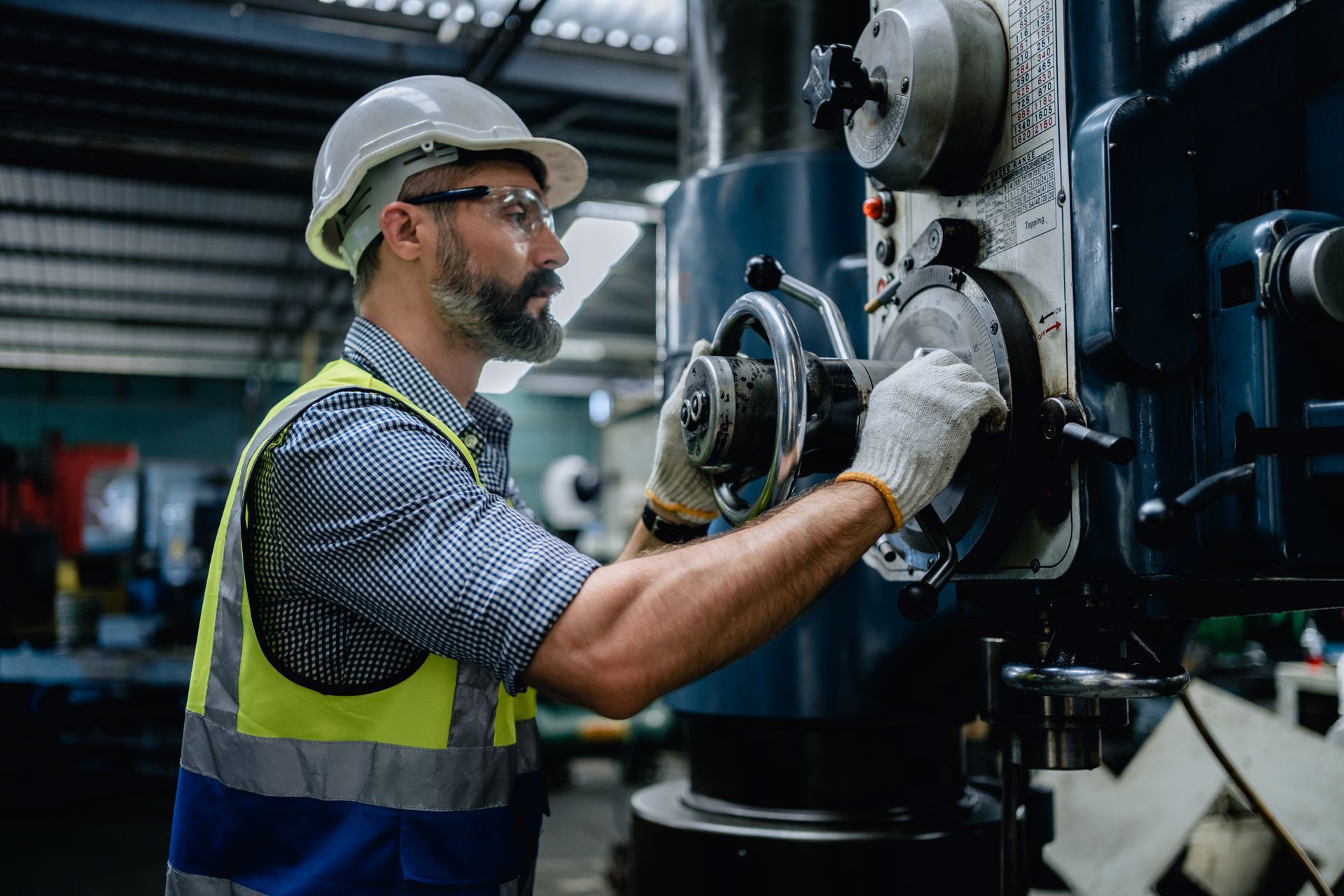 A mechanic in a safety uniform wearing glasses is performing a machinery service A mechanic in a safety uniform wearing glasses is performing a machinery service