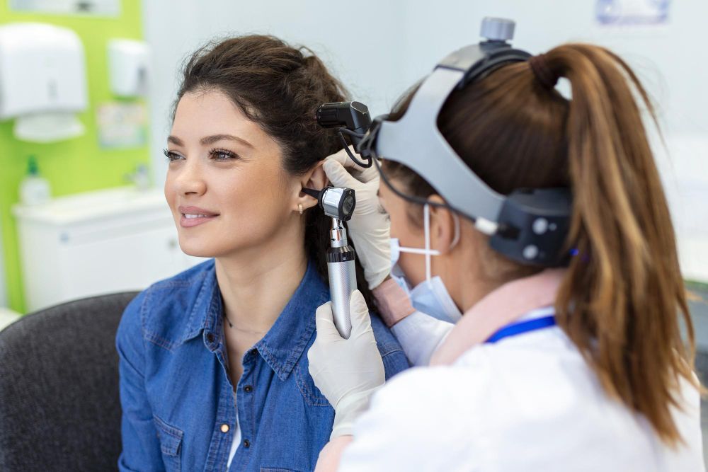Doctor examining a patient’s ear with an otoscope in a clinic