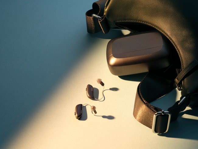 Sunglasses beside a brown case and black bag on a sunlit blue surface.