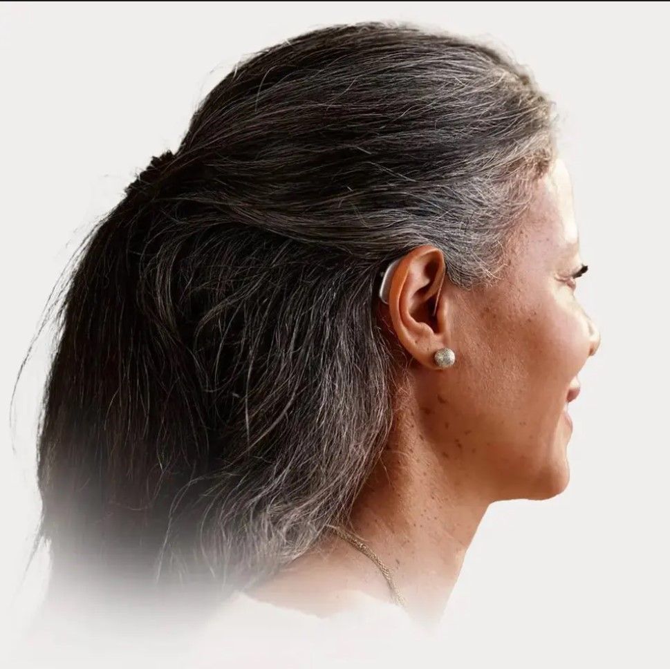 Side profile of a woman with dark hair and pearl earrings on a white background