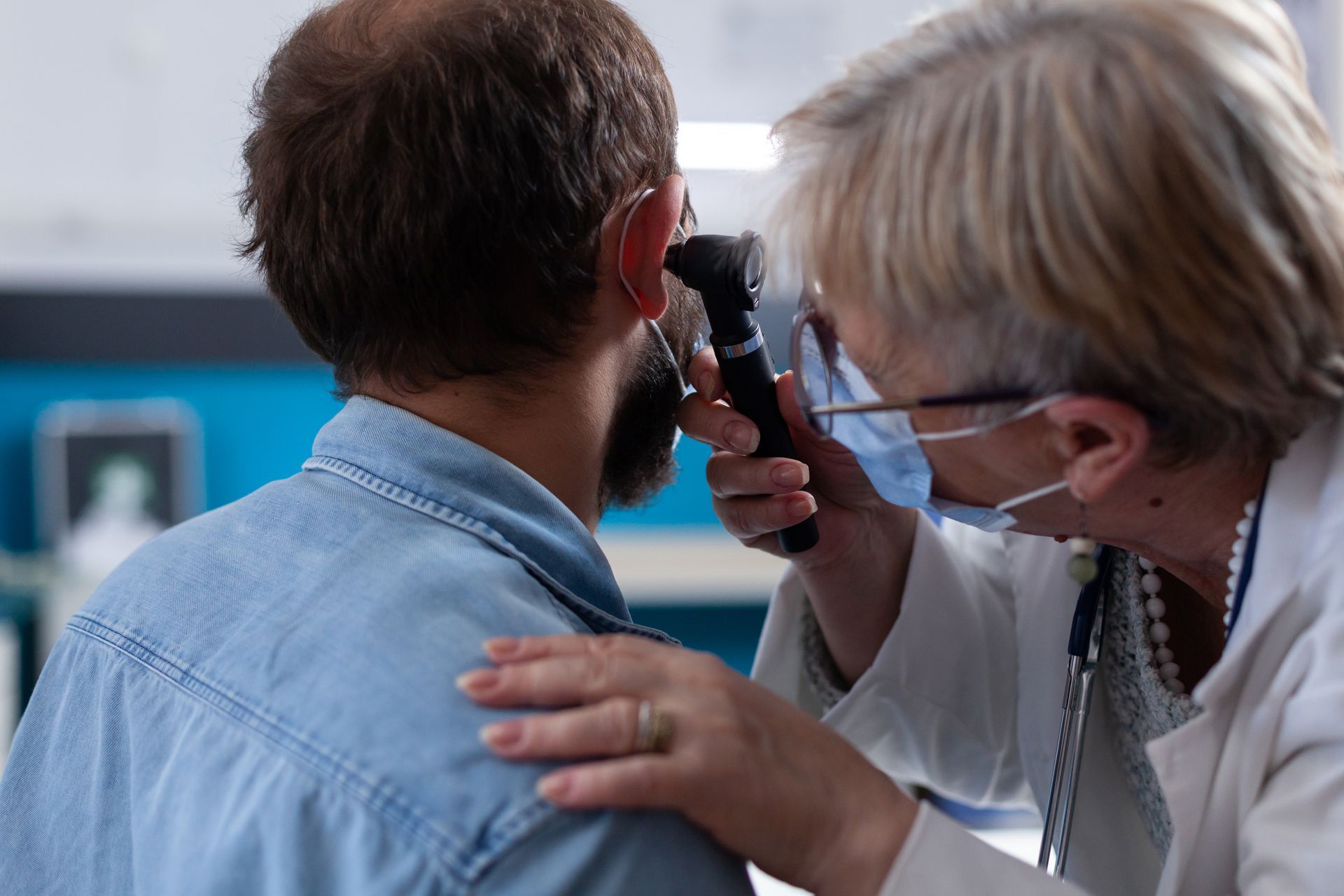 Doctor examining a patient’s ear with an otoscope in a clinic room
