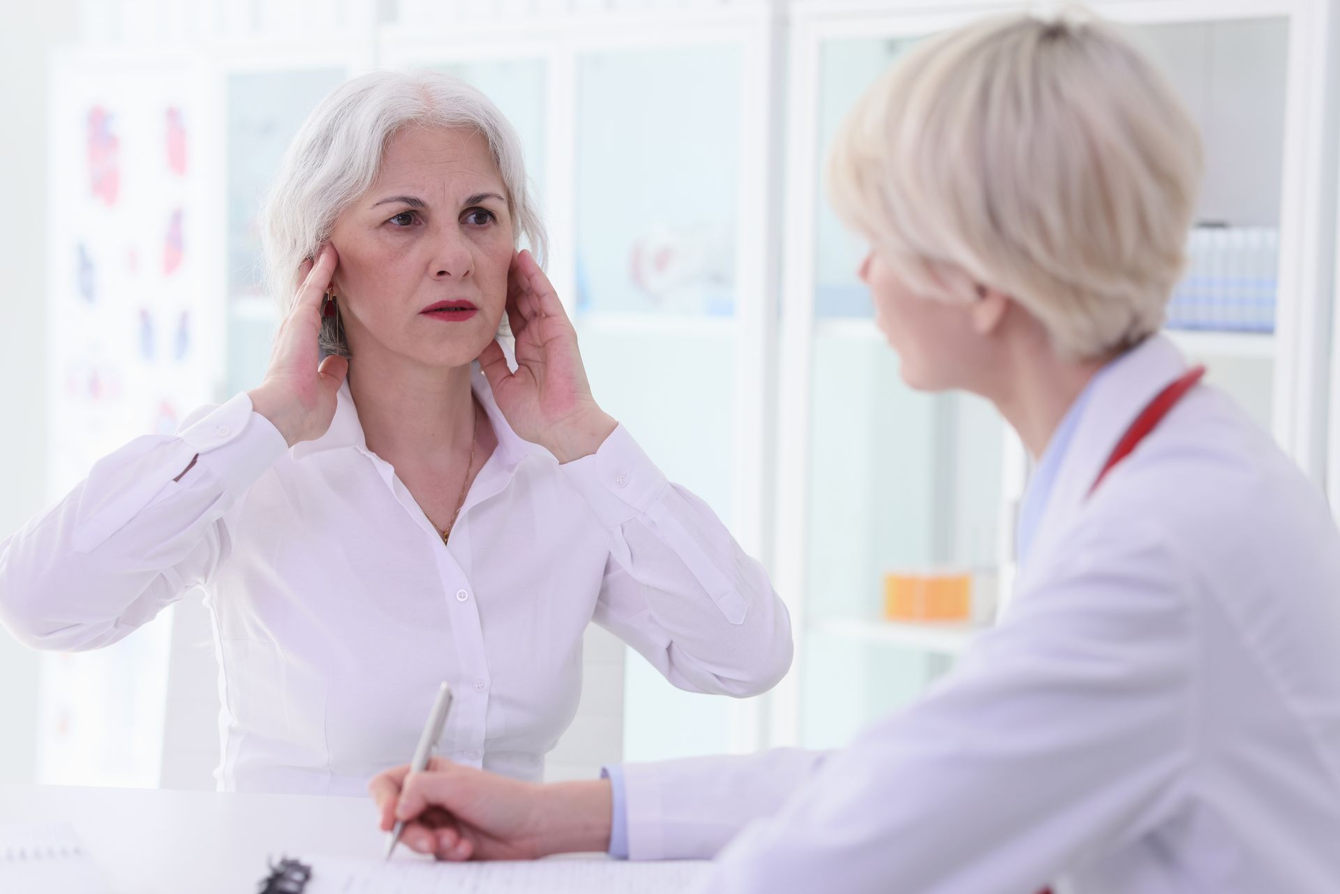 Doctor examining a patient with neck pain in a bright clinic office