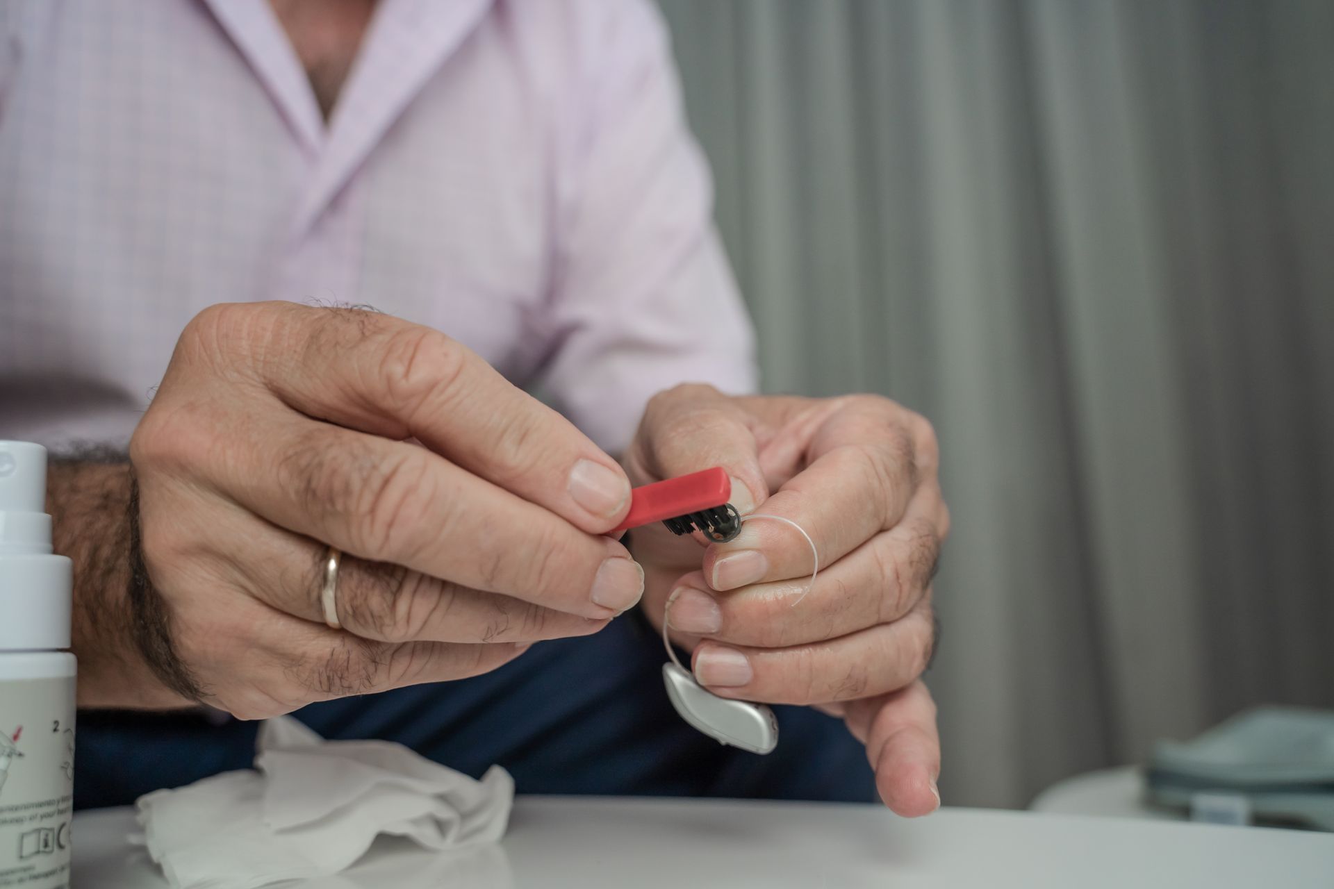 Hands fastening a red strap on a wristwatch at a table