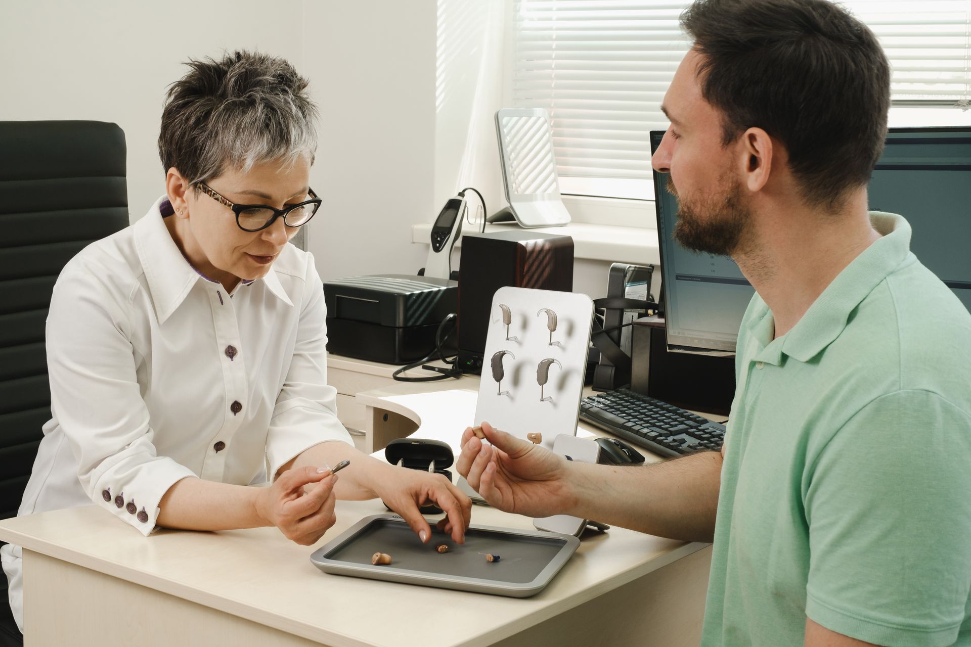 Two people reviewing dental X-rays at a clinic desk with a tablet and computer.