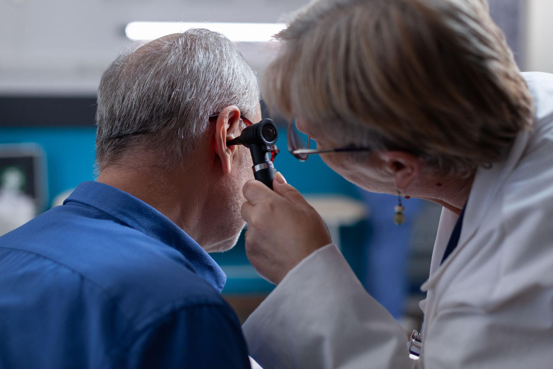 Doctor examining a patient’s ear with an otoscope in a clinic