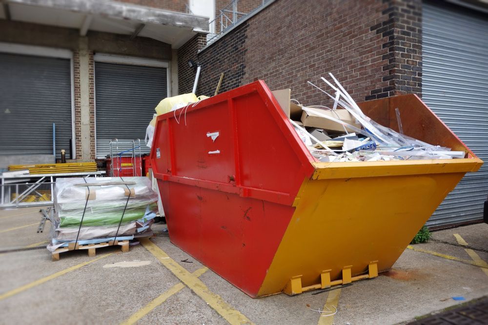 Red And Yellow Dumpster Overflowing With Debris Near A Building — Mount Isa Skips In Camooweal, QLD
