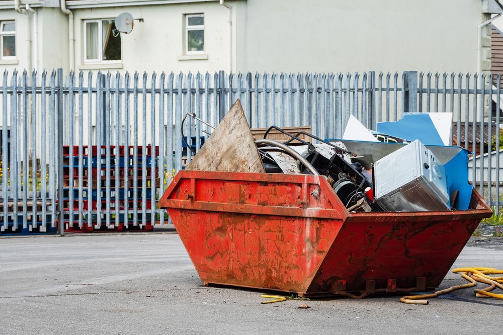 Red Metal Dumpster Filled With Scrap Metal and Wood Sits Outside a Building — Mount Isa Skips In Camooweal, QLD