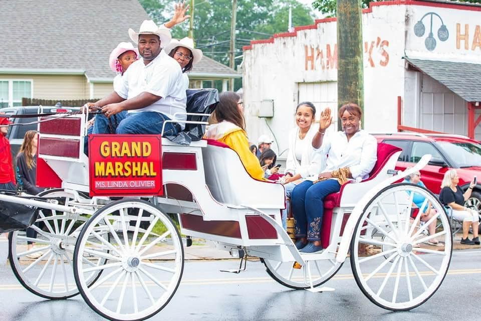 White horse-drawn carriage with passengers and driver in front of a building