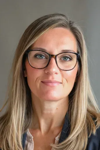Portrait of a person with glasses and blonde hair against a neutral background