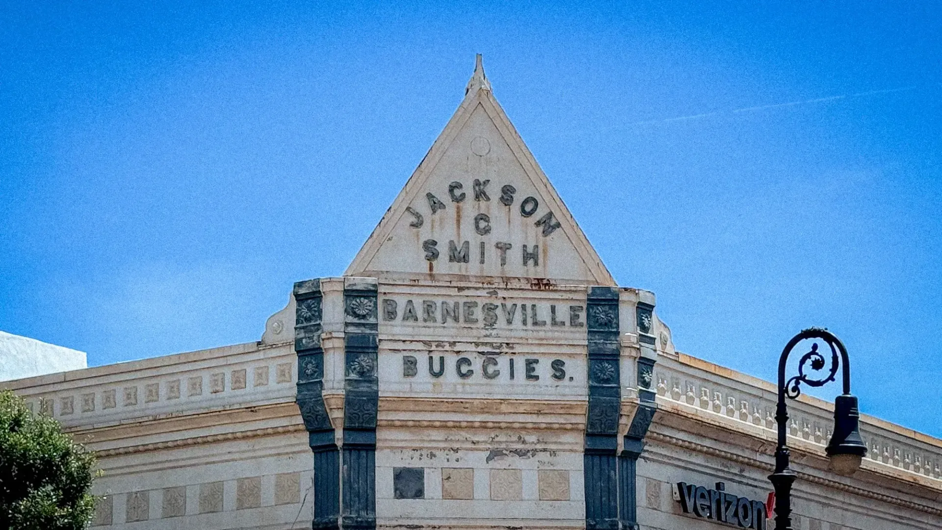 Historic building facade with a triangular roof sign reading “Jackson with Darwinsville Success” against a blue sky