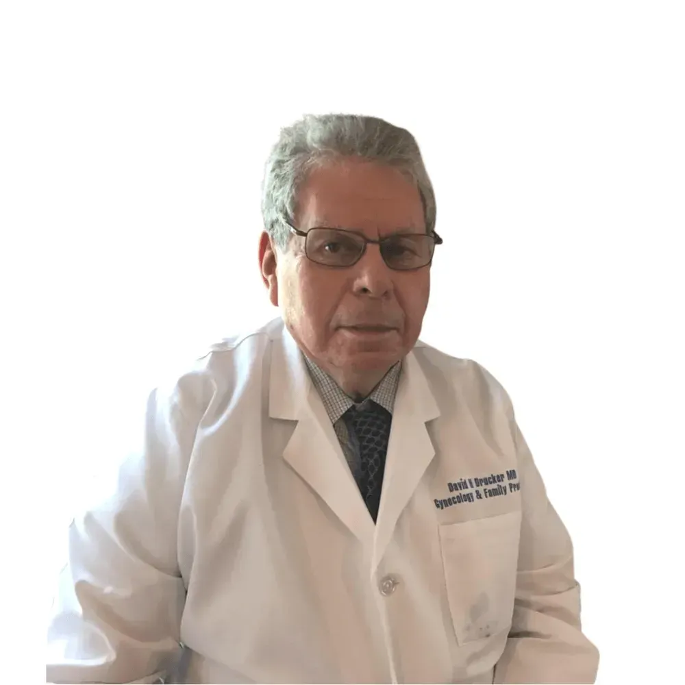 A man in a white coat and tie is sitting in front of a white background.