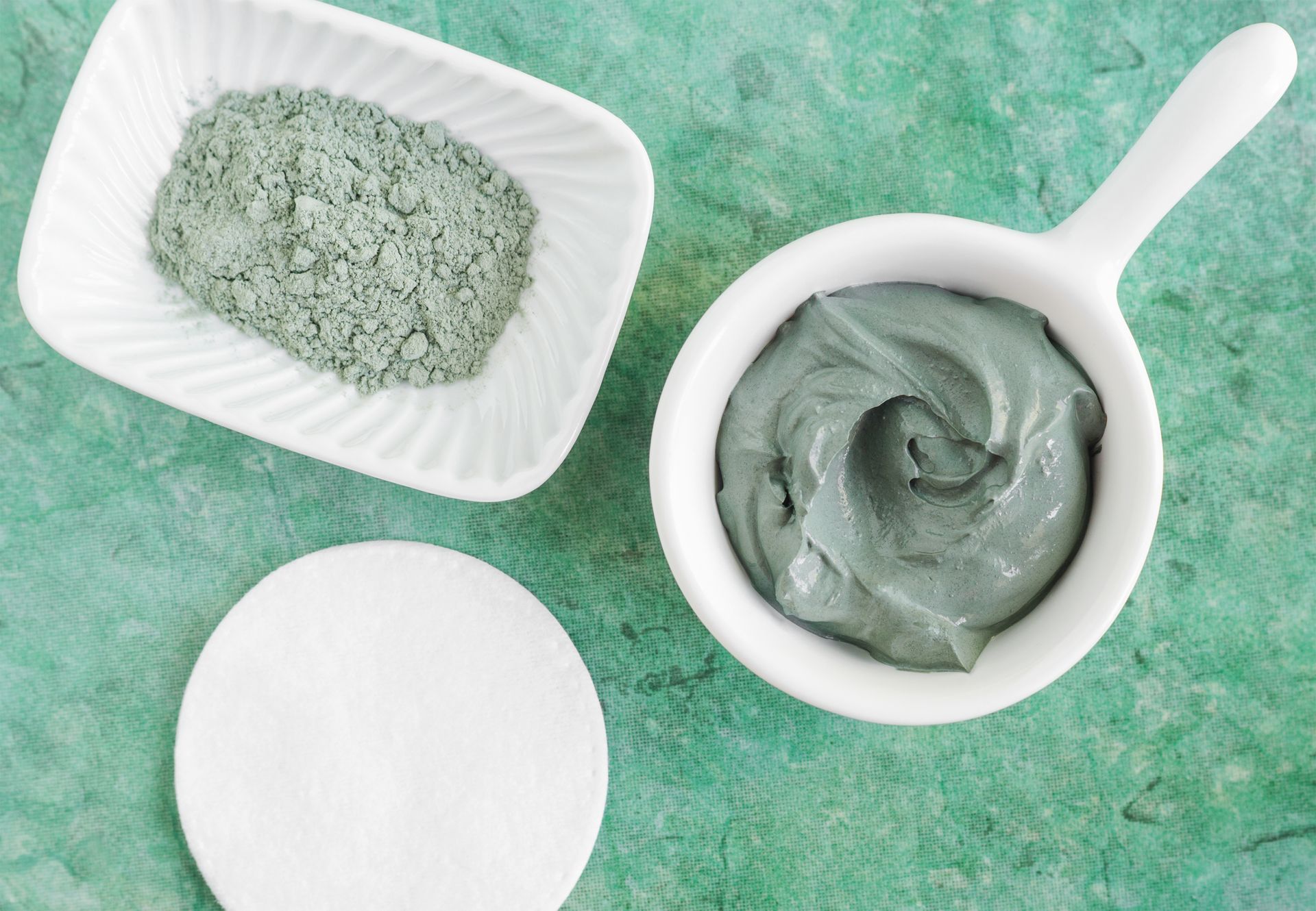 There is a bowl of clay next to a bowl of powder.
