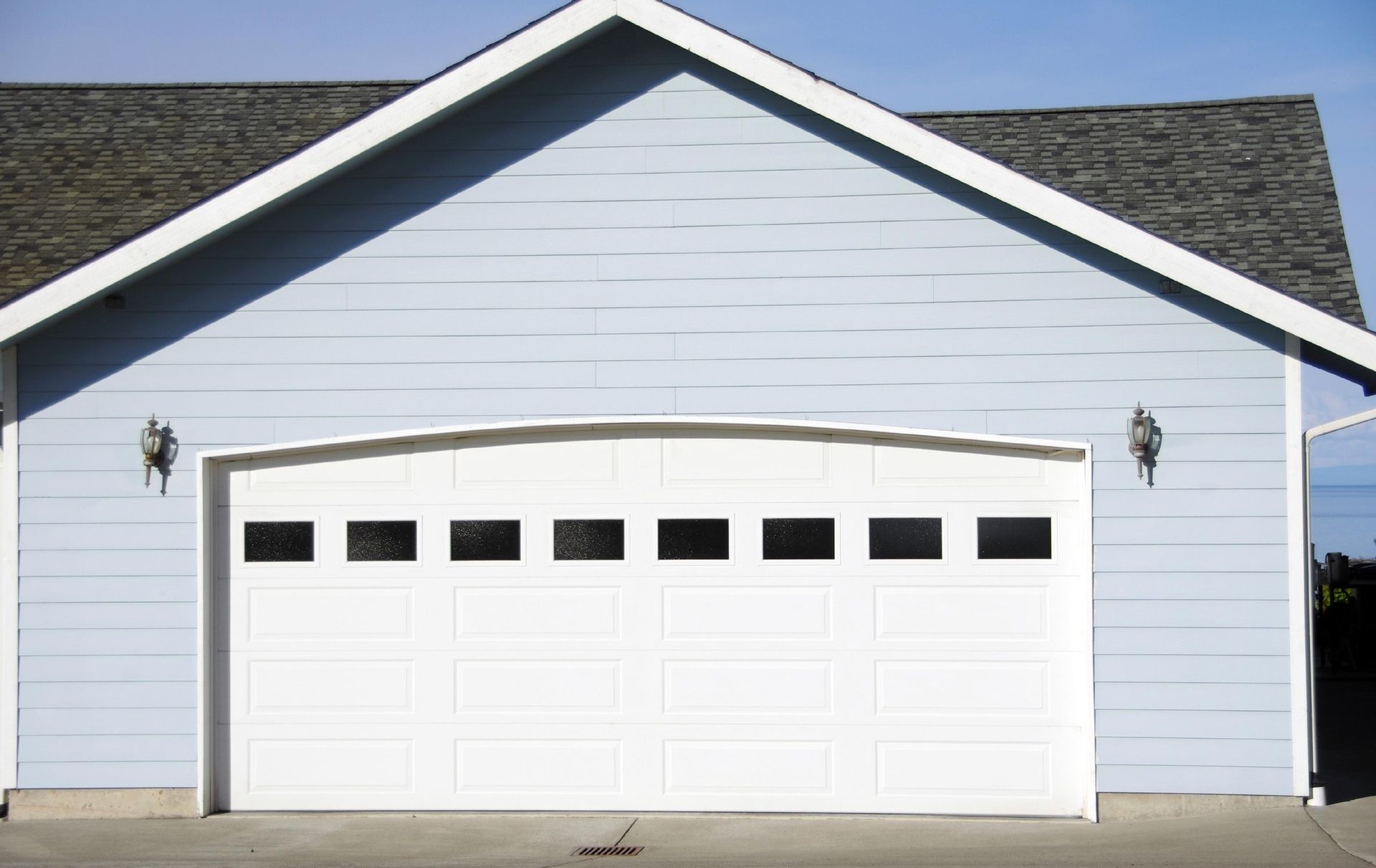 A blue house with a white garage door and a gray roof