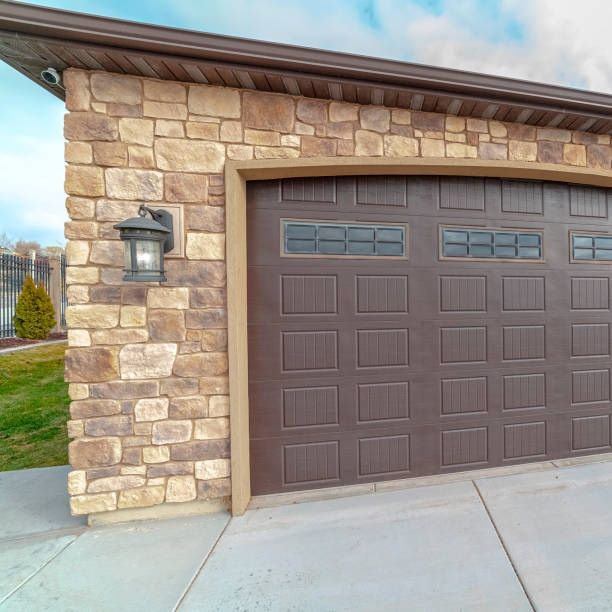 A brown garage door is on the side of a brick building.
