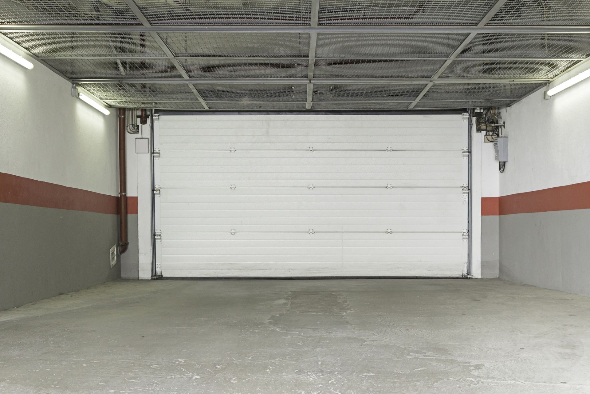 An empty garage with a white garage door open.