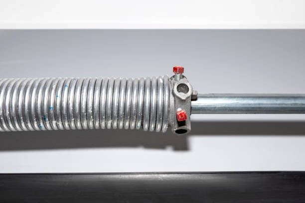 A close up of a garage door spring on a white surface.