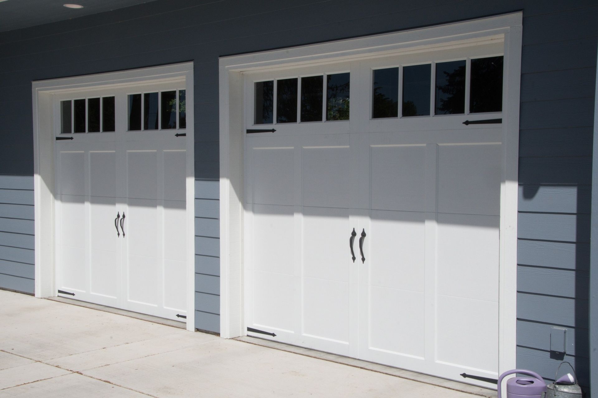 A row of white garage doors on a blue house