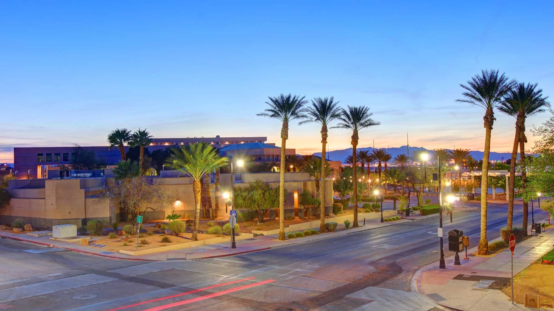 An aerial view of a city street with palm trees at sunset.