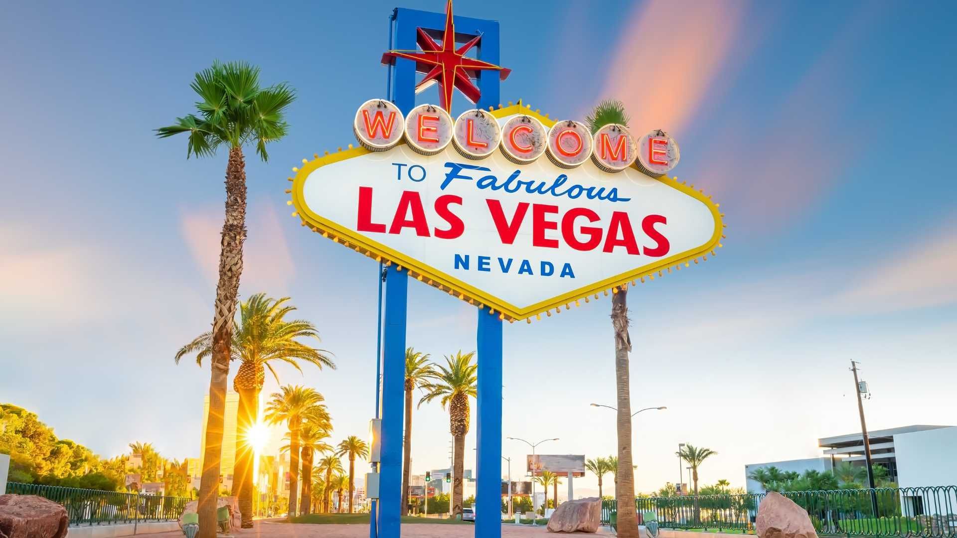 A welcome to las vegas sign with palm trees in the background.
