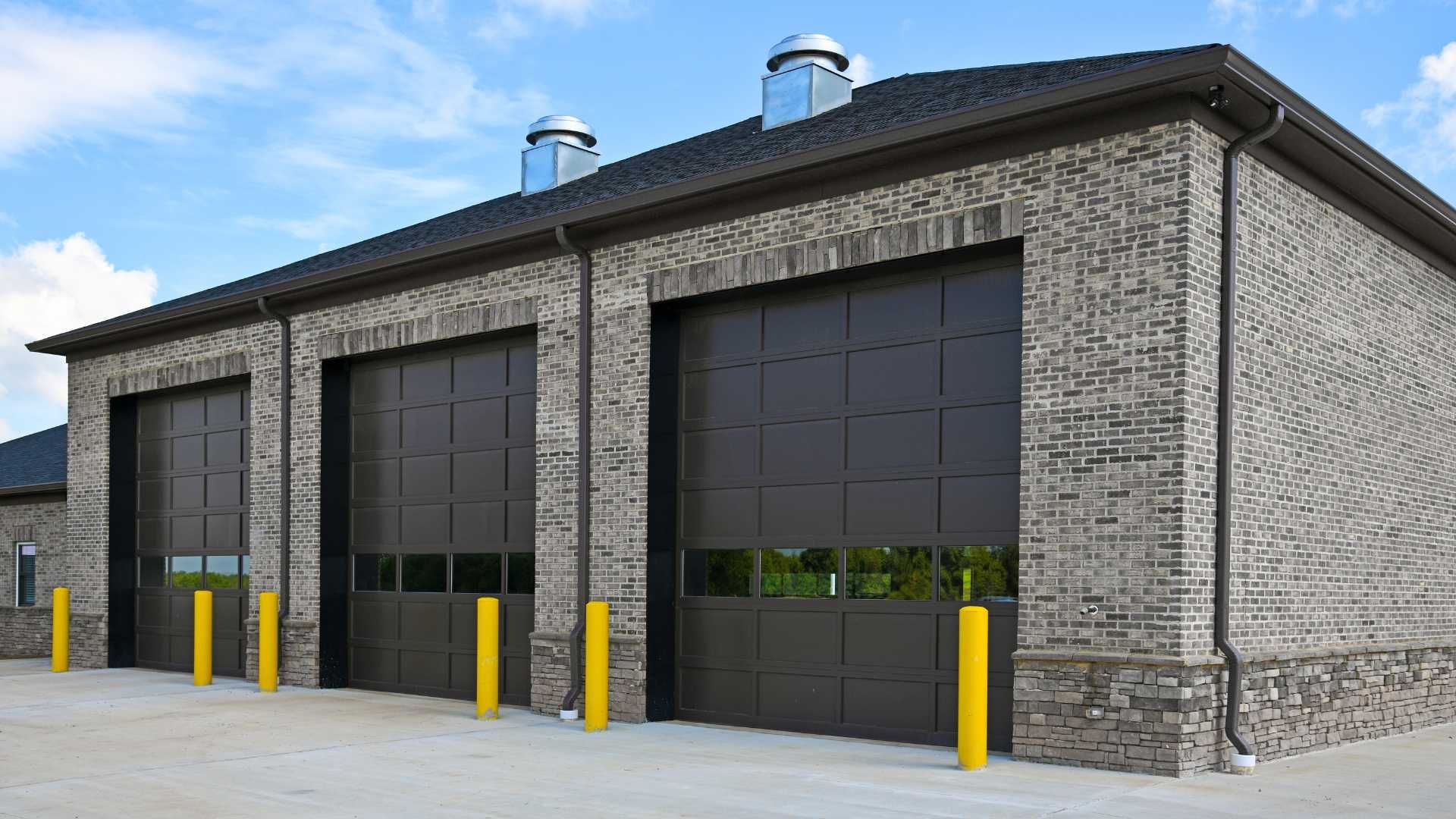 A row of garage doors are lined up in front of a brick building.