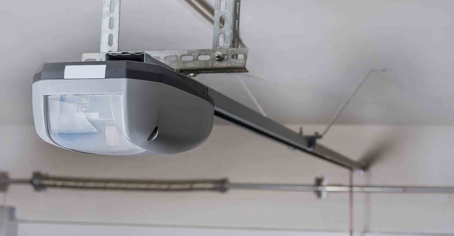 A garage door opener is hanging from the ceiling of a garage.
