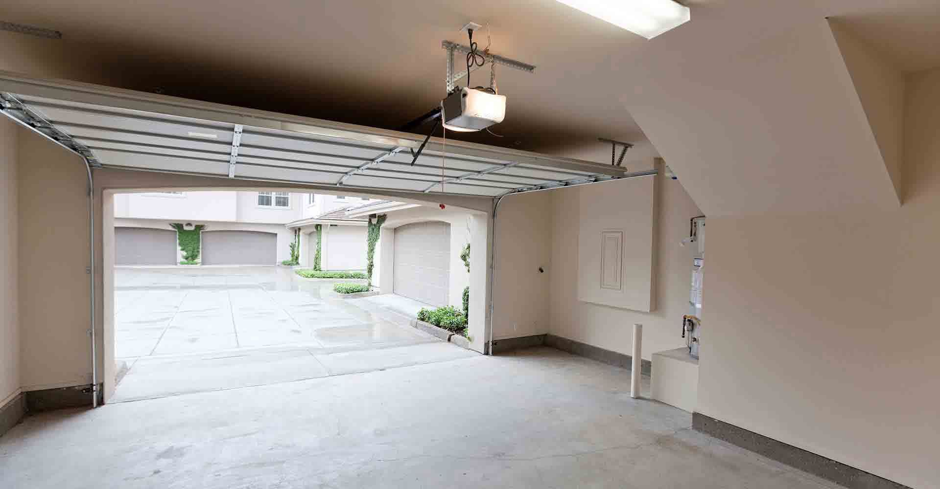 An empty garage with the door open and a garage door opener.