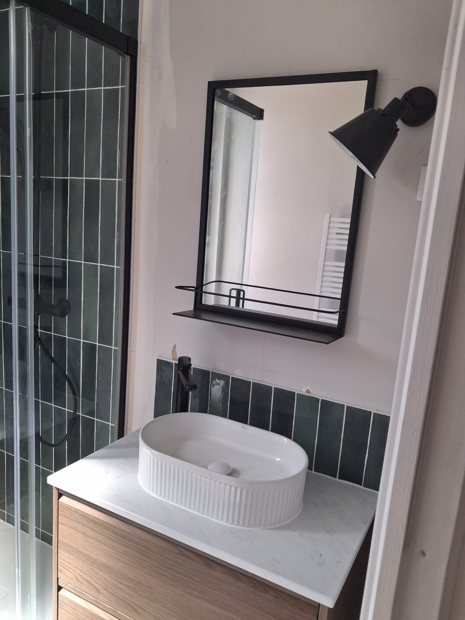Salle de bains rénovée à Fécamp avec vasque cannelée, miroir noir et faïence verte