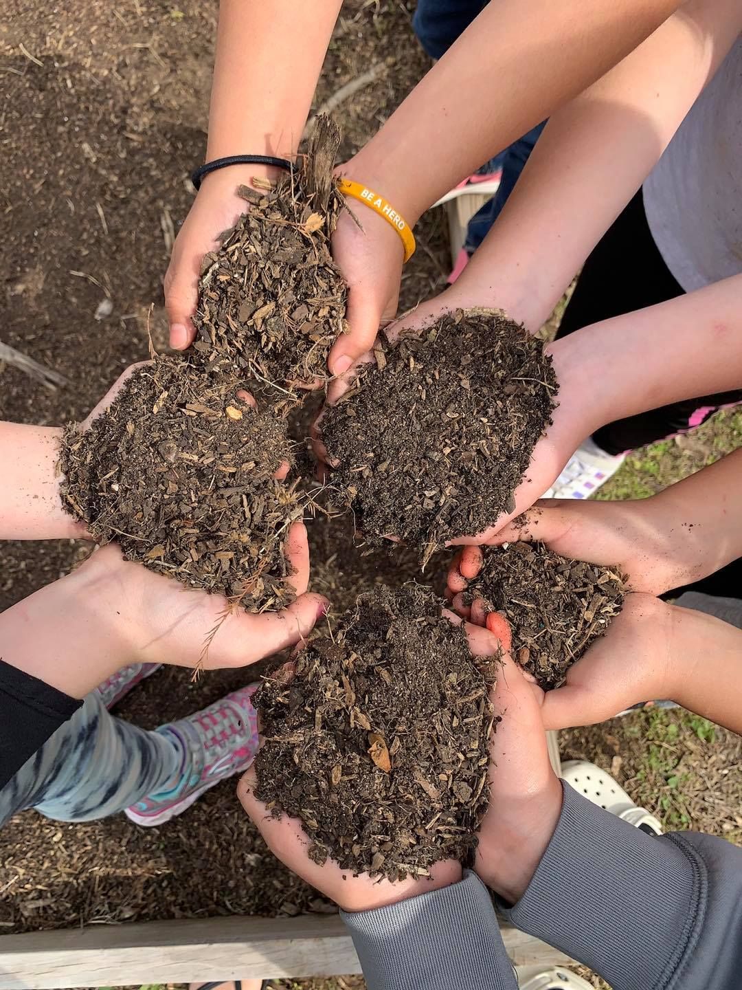 A group of children are holding a pile of dirt in their hands.