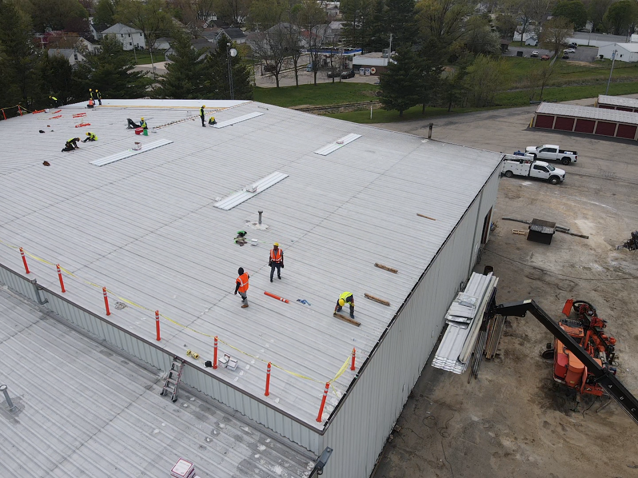 Aerial view of crews working across a large metal commercial roof.