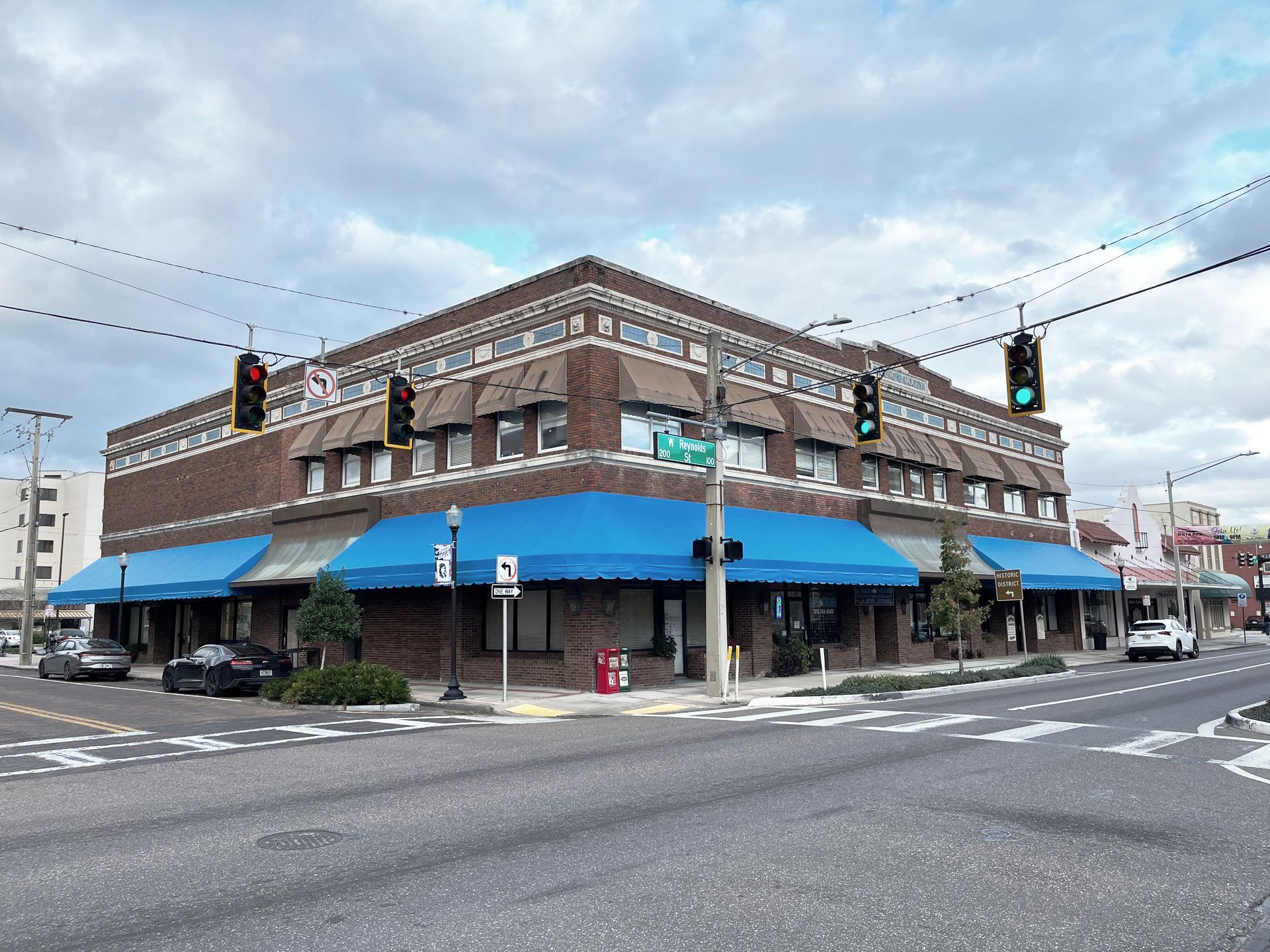 Brick corner storefront with blue awnings at a snowy intersection under traffic lights