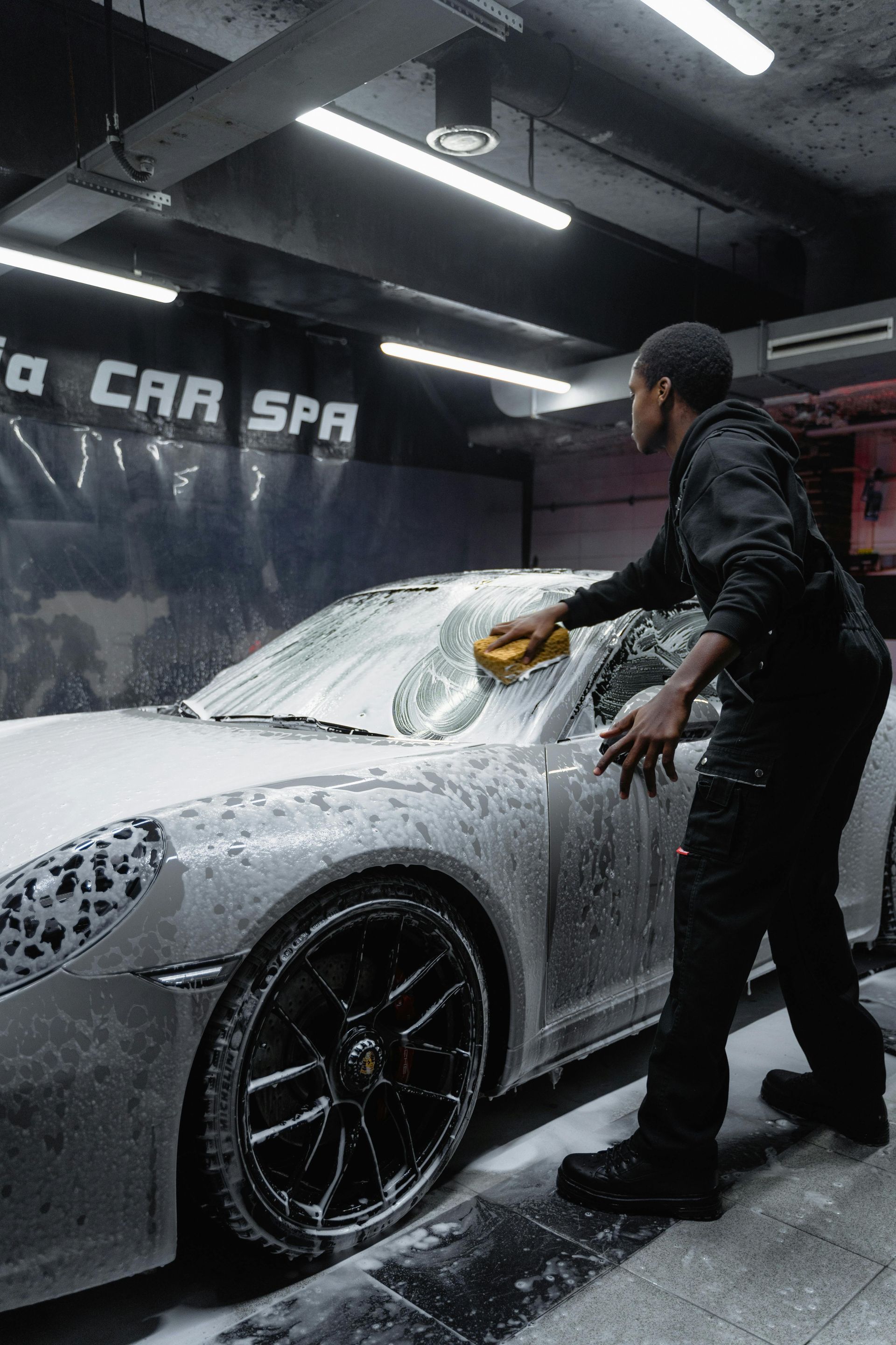 Man washing a white car with foam at a car wash.