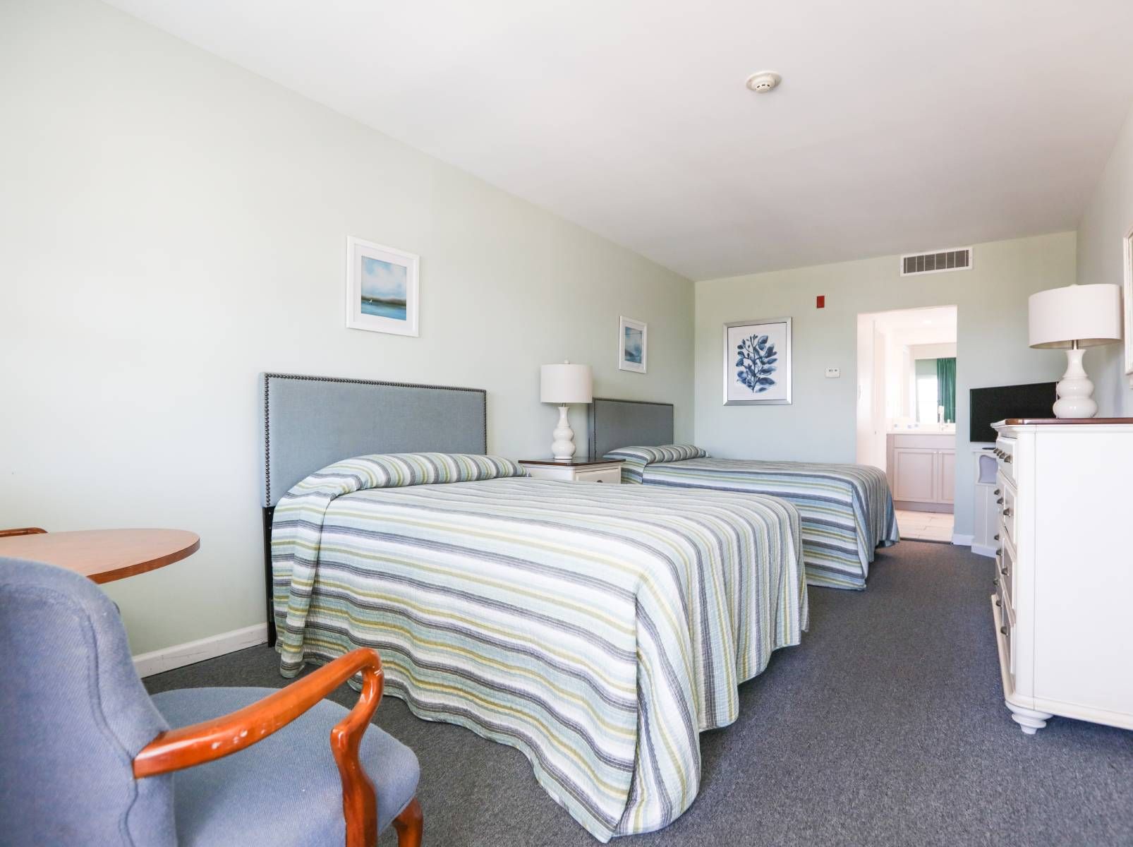 A hotel room with two beds , a dresser and a mirror.
